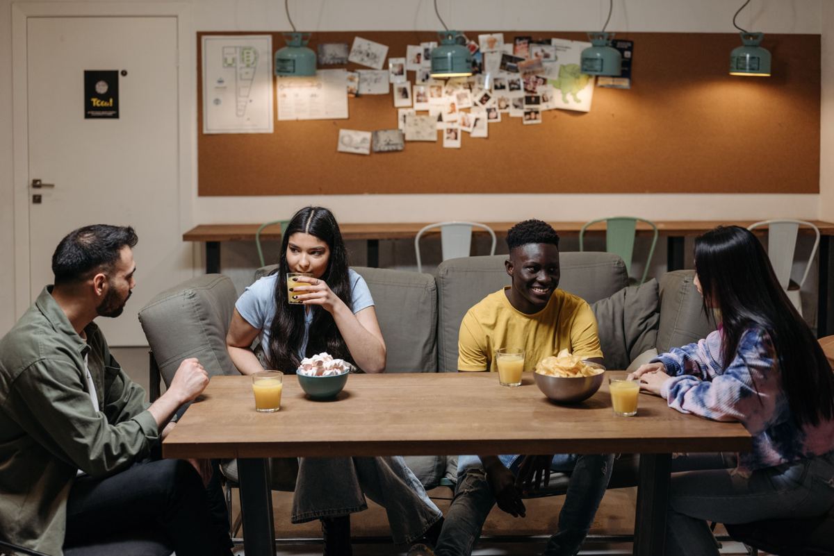 Four housemates talking and sharing snacks around a table