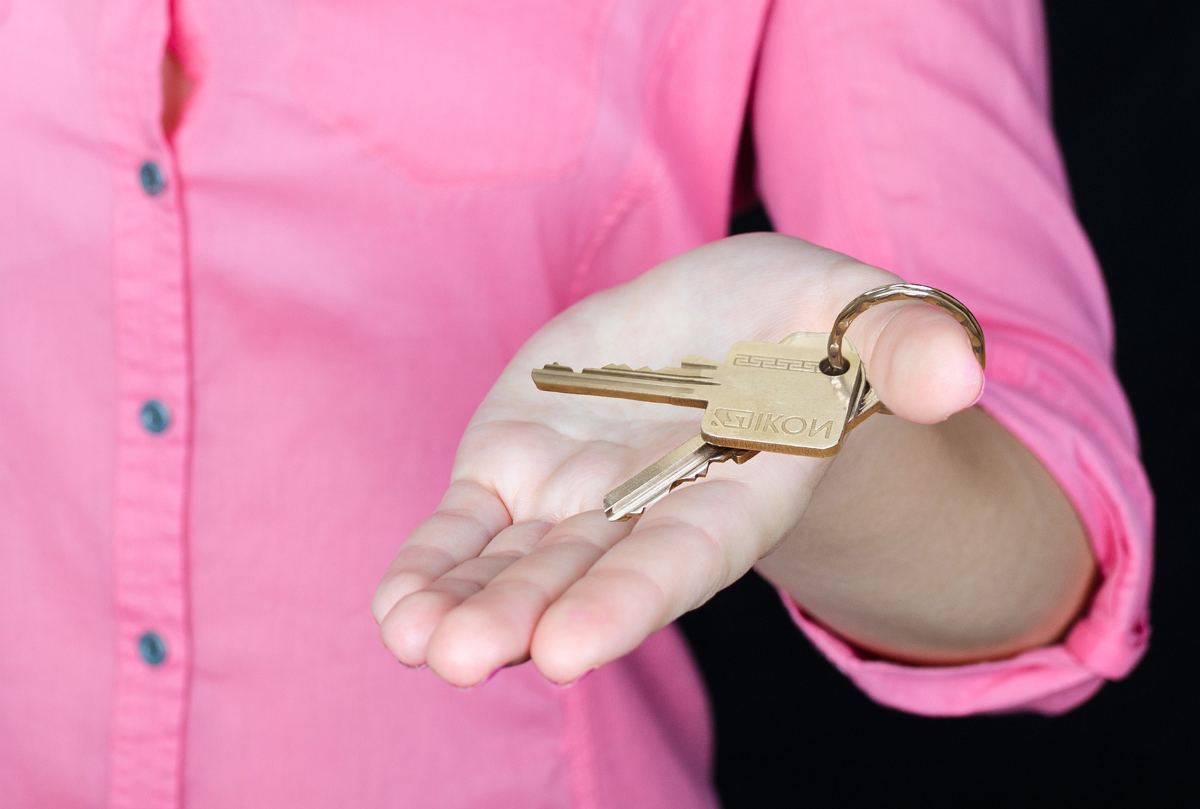 A hand holding out a set of house keys